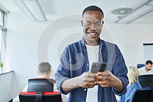 Joyful young man using mobile phone in coworking office