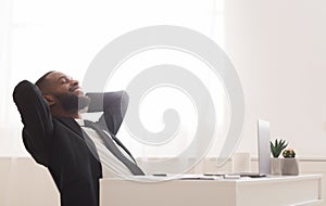 Joyful young manager relaxing on chair in white modern office