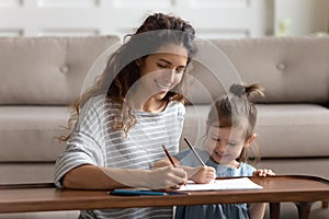 Joyful young mommy drawing cute pictures with adorable daughter.