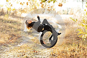 Joyful young mother having fun with her little son in nature, sitting together on a swing wheel