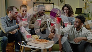 Joyful young people multiethnic group toasting drinking having fun at party at home at night