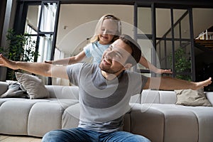 Joyful young single father playing with cute small preschool daughter.