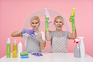 Joyful young white-headed lovely woman with casual hairstyle raising hands with detergents and smiling happily while her
