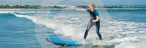 Joyful young woman beginner surfer with blue surf has fun on small sea waves. Active family lifestyle, people outdoor
