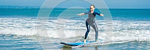 Joyful young woman beginner surfer with blue surf has fun on small sea waves. Active family lifestyle, people outdoor photo
