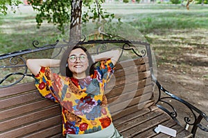 Joyful young woman enjoying a peaceful moment on a park bench with music.