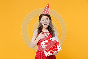 Joyful young woman girl in red summer dress birthday hat isolated on yellow background. Birthday holiday concept. Mock