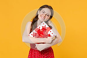 Joyful young woman girl in red summer dress posing isolated on yellow wall background studio portrait. Birthday holiday