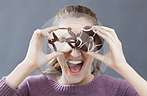 Joyful young woman hiding eyes with donuts for fun joke