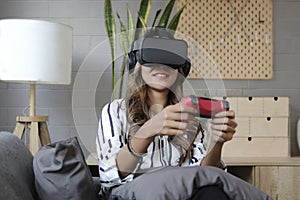 Joyful young woman holding joystick console playing video games on virtual reality headset. Futuristic environment, leisure