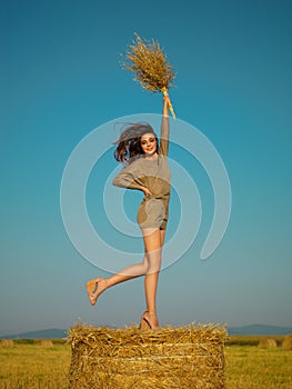 Joyful young woman jumping on hay stack