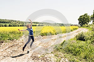 Joyful young woman is jumping in rapeseed field