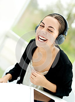 Joyful young woman laughing and listening to music