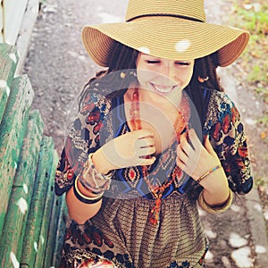 Joyful young woman portrait with dreadlocks dressed in boho style dress and necklace, sunny outdoor