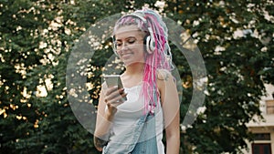 Joyful young woman with smartphone dancing outdoors wearing headphones
