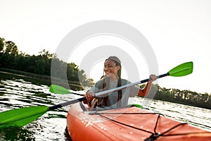 Joyful young woman smiling, enjoying a day kayaking together with her friend in a lake on a late summer afternoon