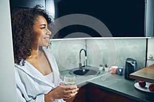 Joyful young woman standing in the kitchen