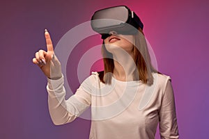 joyful young woman in virtual reality helmet, looking into VR glasses screen