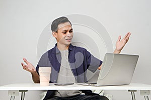 joyfull happy asian man at workplace while sitting in front of laptop computer. on isolated background