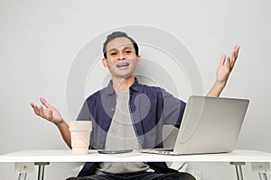 joyfull happy asian man at workplace while sitting in front of laptop computer. on isolated background