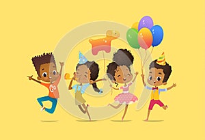 Joyous African-American boys and girls with the balloons and birthday hats happily jumping with their hands up. Birthday