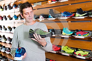 Joyous athlete chooses sporty clothes and comfortable shoes in the sports shop