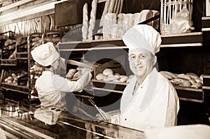 Joyous bakers with fresh bread in bakery