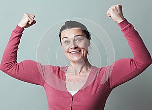 Joyous beautiful 40s woman flexing her muscles up