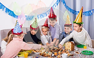 Joyous boys and girls having dinner to birthday