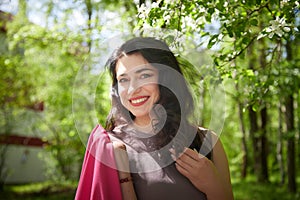 Joyous brunette woman near Blossoms of apple tree in a Spring Garden outdoors. Concept of face and body care. The scent