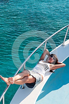 Joyous brunette woman in synglasses laying on deck