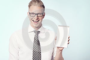 Joyous businessman presenting blank notepad.