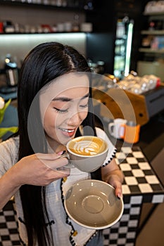 Joyous cafe visitor enjoying her cappuccino with foam