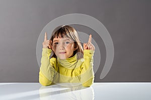 Joyous cheeky child enjoying raising his fingers for fun answers