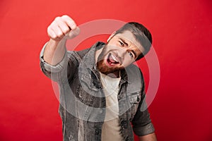 Joyous cheerful man 30s in jeans jacket smiling and pointing ind