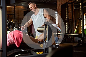 Joyous coach sharing tips on exercising with woman at gym