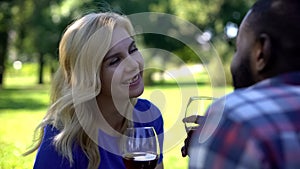 Joyous couple toasting and drinking wine in park, romantic date and picnic