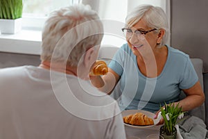 Joyous female feeding up her spouse with a tasty croissant.