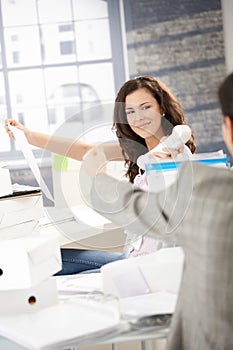 Joyous female passing phone to colleague in office photo