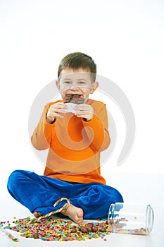 Joyous kid eating chocolate sitting cross-legged photo