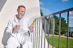 Joyous mature holidaymaker reading a text message on his phone