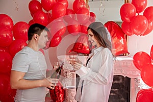 Joyous moment between young couple celebrating with toast Valentines day near red balloons