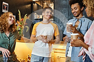 joyous multiethnic buddies with takeaway drinks