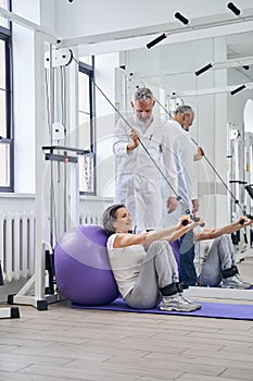 Joyous patient doing arm workout using the gym equipment