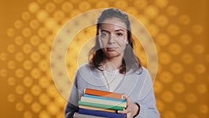 Joyous person walking with pile of novels, feeling delighted, studio background