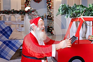 Joyous Santa Claus enjoying with modern gadget. photo