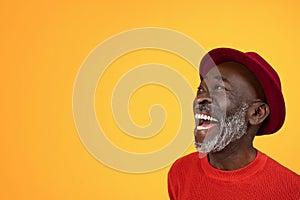 Joyous senior Black man with a white beard, looking up and laughing in delight