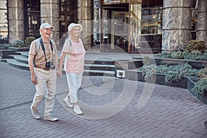 Joyous senior tourist couple sauntering along the street