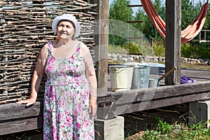 Joyous senior woman standing near house wall