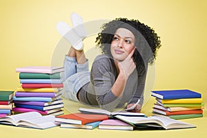 Joyous student girl reading surrounded by colorful books.